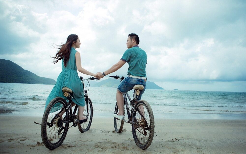 手をつないで自転車に乗っているカップル
